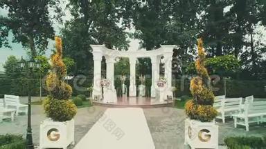 向后鸟瞰美丽的婚礼，白色<strong>拱门</strong>和美丽的绿色公园区地毯。
